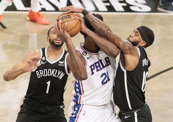 Joel Embiid, pívot estrella de los 76ers de Filadelfia, fue registrado este jueves, 20 de abril, al defender un balón, ante la marca de Mikal Bridges (i) y Royce O'Neale (d) de los Nets de Brooklyn, durante un partido de los 'playoff' de la Conferencia Este de la NBA, en el coliseo Barclays Center, en Brooklyn (Nueva York, EE.UU.). EFEJustin Lane