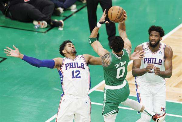 El alero de los Celtics Jayson Tatum (c) dispara sobre el delantero defensor de los 76ers Tobias Harris (i) y el centro de los 76ers Joel Embiid (d). EFE/EPA/CJ GUNTHER
