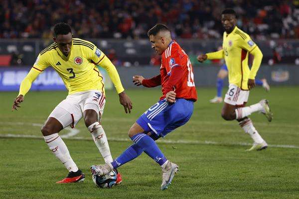 Alexis Sánchez (d) de Chile disputa el balón con Jhon Lucumí de Colombia hoy, en un partido de las Eliminatorias Sudamericanas para la Copa Mundial de Fútbol 2026 entre Chile y Colombia en el estadio Monumental en Santiago de Chile (Chile). EFE/ Elvis González