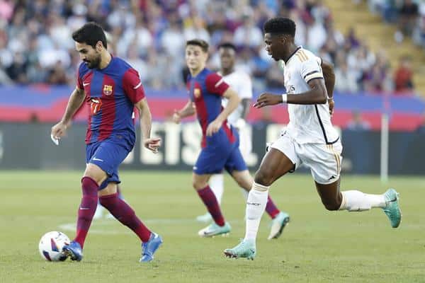 Ilkay Gündogan (i) centrocampista alemán del FC Barcelona, disputa un balón ante Aurélien Tchouaméni (d) centrocampista francés del Real Madrid durante el partido de LaLiga que enfrentó al FC Barcelona y al Real Madrid en el Estadio Olímpico Lluís Companys de BarcelonaEFE/ Andreu Dalmau