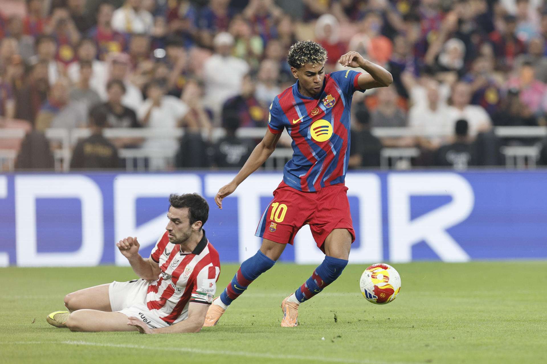 El delantero del FC Barcelona, Lamine Yamal (d), se lleva el balón ante el defensa del Athletic Club, Iñigo Lekue, durante la semifinal de la Supercopa de España. EFE/ Kai Forsterling