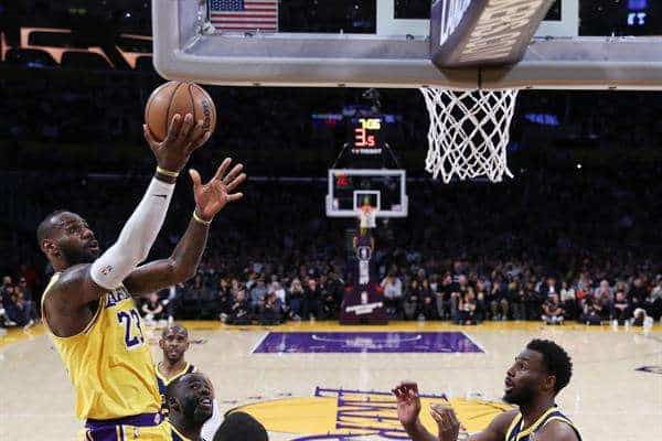 El alero estrella de los Lakers de Los Ángeles, LeBron James (i), fue registrado el pasado 9 de abril al atacar el aro que defendían los Warriors de Golden State, en Los Ángeles (California, EE.UU.). James aportó este domingo, 14 de abril, un triple-doble de 28 puntos, 11 rebotes y 17 asistencias, para guiar el triunfo a domicilio de su equipo 108-124 sobre los Pelicans de Nueva Orleans, con quienes disputarán el 'play in' de repechaje por el último cupo de la conferencia Oeste en las series finales de la NBA. EFE/Caroline Brehman