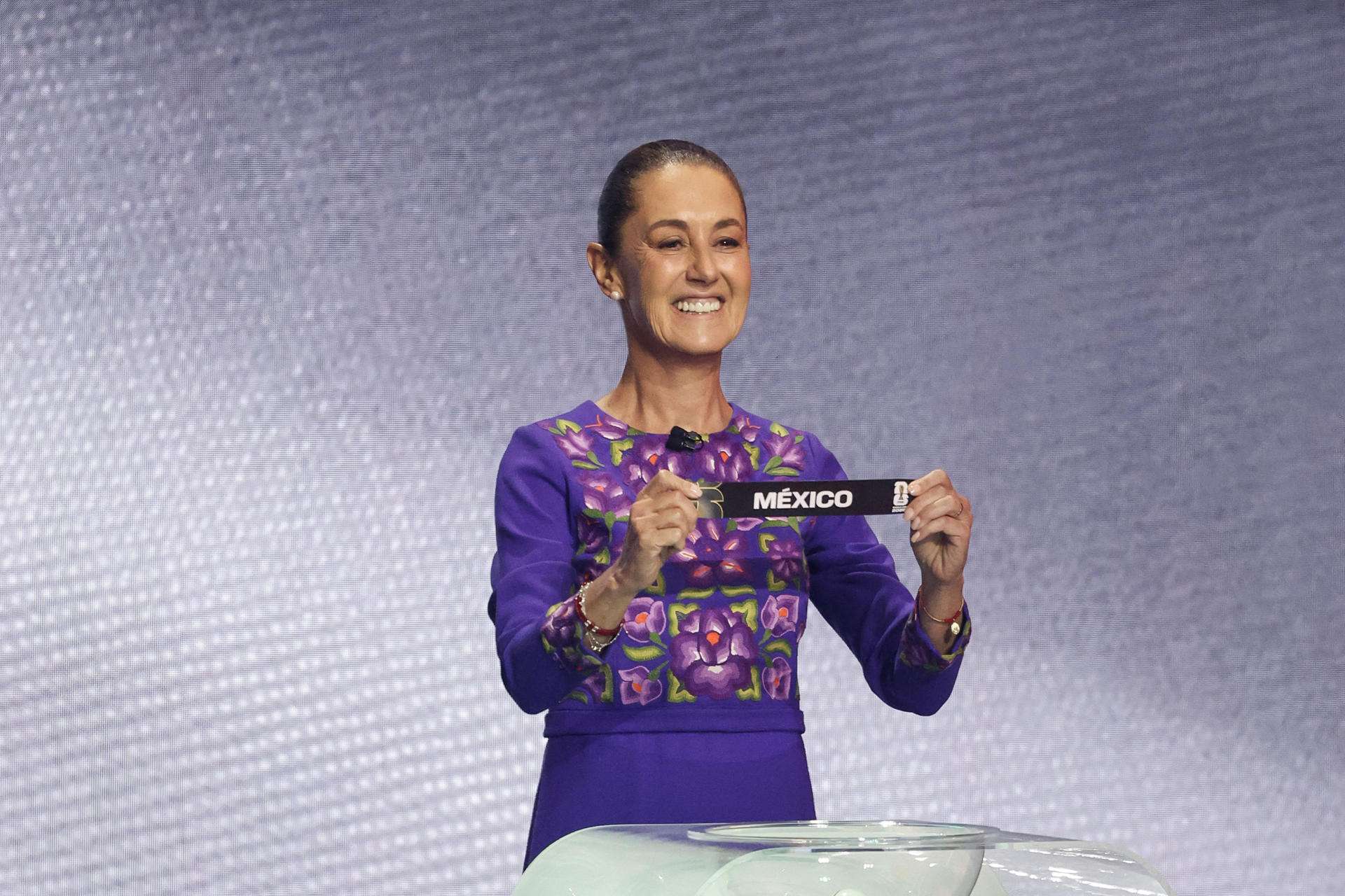 La presidenta de México, Claudia Sheinbaum, sostiene un papel con el nombre de su país durante el sorteo del Mundial de Fútbol FIFA 2026. EFE/ Octavio Guzmán